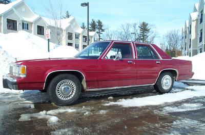 1991 Ford Crown Victoria LTD - Side view of a red 1991 Ford Crown Victoria LTD sedan in a snowy parking lot.