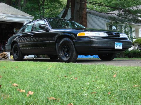 2003 Ford Crown Victoria - A black 2003 Ford Crown Victoria sedan is parked in front of a house and garage.