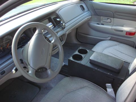 2003 Ford Crown Victoria - The interior of a 2003 Ford Crown Victoria features a gray dashboard, steering wheel, and cloth seats, along with an aftermarket center con…