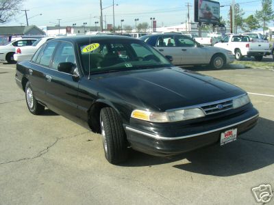 2003 Ford Crown Victoria - A black Ford Crown Victoria is parked in a lot, with a '1997' tag visible on the windshield.