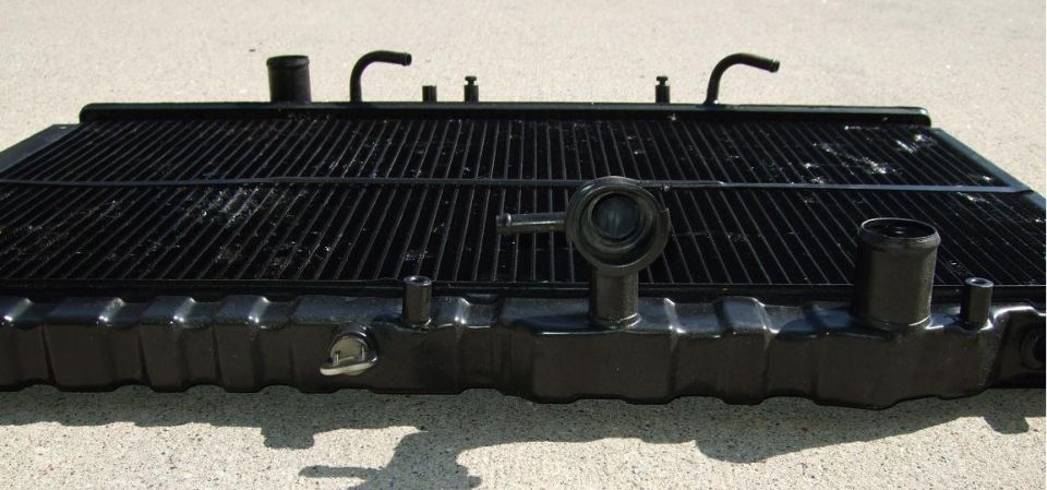 Black car radiator with visible fins and hose connections