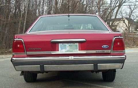 1991 Ford LTD Crown Victoria - Straight-on rear view of a burgundy Ford LTD Crown Victoria sedan showing the "LTD Crown Victoria" trunk badge, Ford blue oval, chrome rear…
