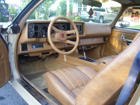 1979 Chevrolet Camaro - The interior of a 1979 Chevrolet Camaro features tan upholstery, a wood-grain dashboard, and a prominent steering wheel.