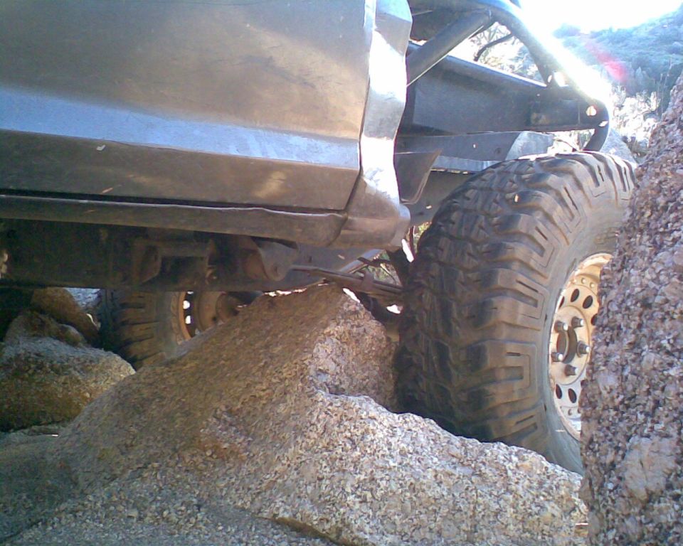 Off-road vehicle with large tires navigating rocky terrain. Roll cage visible