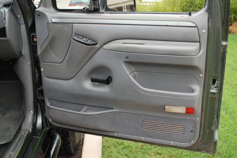 1994 Ford Bronco - The interior door panel of a vehicle is shown, with visible storage and controls.