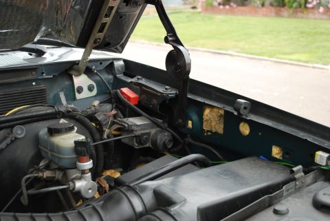 1994 Ford Bronco - The engine bay of a vehicle is shown with the hood open, revealing various components and wiring harnesses.