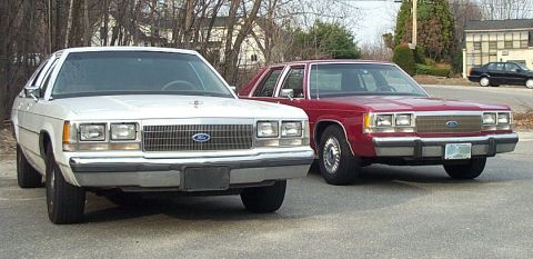 1991 Ford LTD Crown Victoria - Two Ford Crown Victorias are parked on the street, showing their front ends.