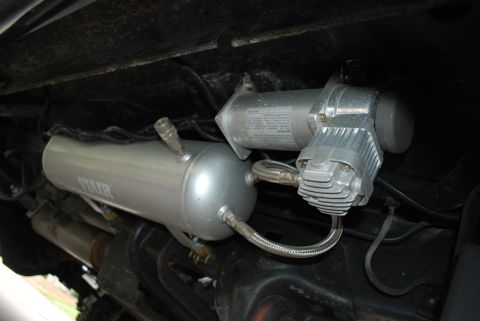 1994 Ford Bronco - Underside view of an air compressor and tank system installed on a vehicle.