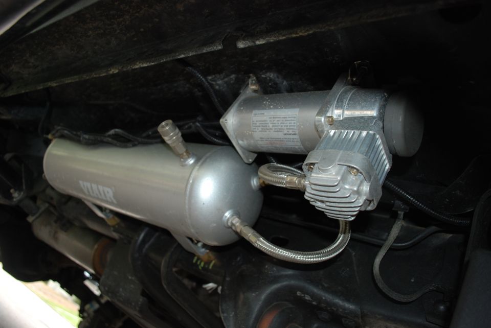 Air compressor and tank mounted under a vehicle, with visible text 'VIAIR' on the tank