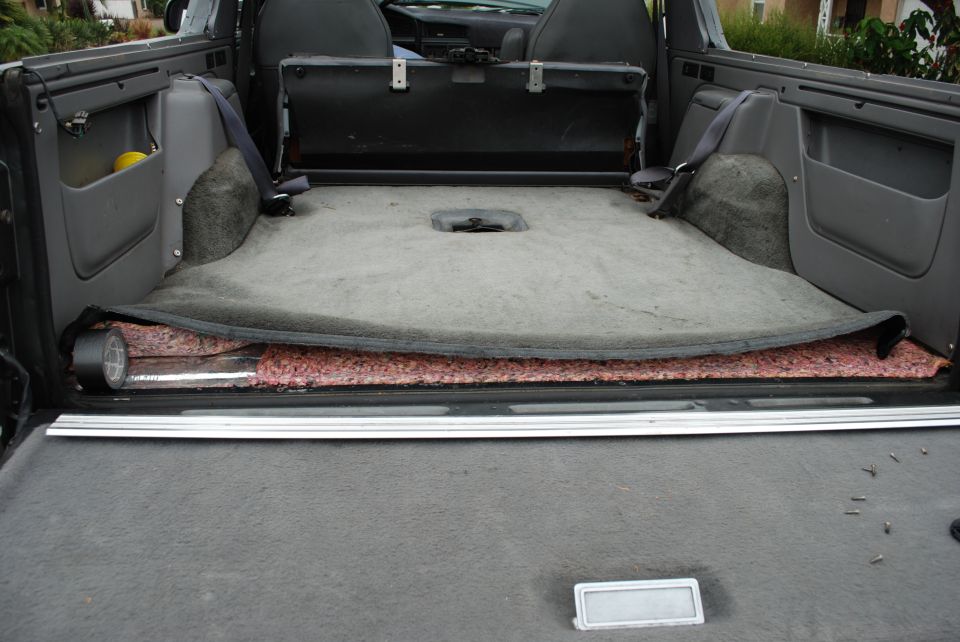 1994 Ford Bronco interior cargo area with carpet pulled back showing insulation and tape