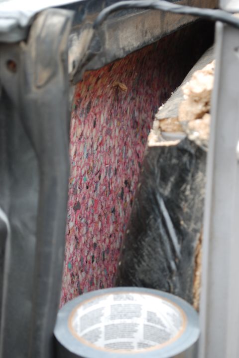 1994 Ford Bronco - A roll of duct tape is visible below exposed insulation within a dark vehicle compartment.
