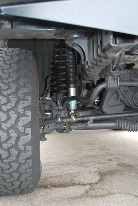 1994 Ford Bronco - Close-up view of the front suspension system and tire of an off-road vehicle.