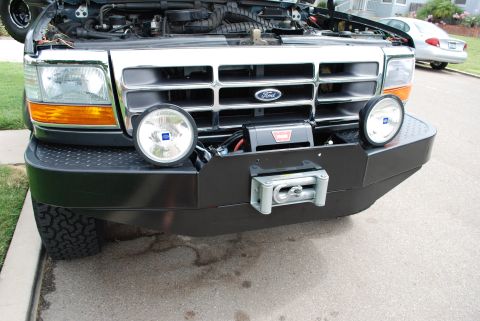 1994 Ford Bronco - Front view of a 1994 Ford Bronco an aftermarket bumper with a winch and fog lights. The hood is open.