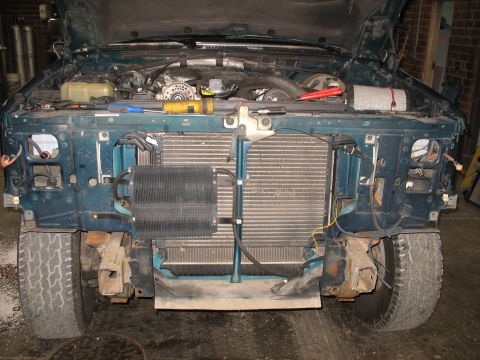 1995 Ford C-350 (Centurion Conversions) - The front of a truck is disassembled, revealing the engine, radiator, and an auxiliary cooler.