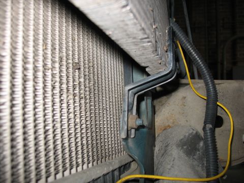 1995 Ford C-350 (Centurion Conversions) - Close-up of a vehicle's radiator and its mounting hardware, showing a section of the cooling fins.