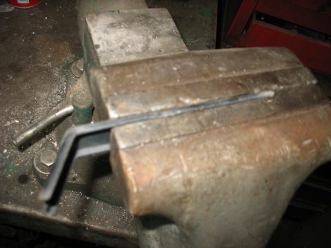 1995 Ford C-350 (Centurion Conversions) - A metal bracket is held firmly in a vise, ready for modification or repair.