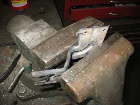 1995 Ford C-350 (Centurion Conversions) - A metal bracket is held in a vise, suggesting it is being worked on or repaired.