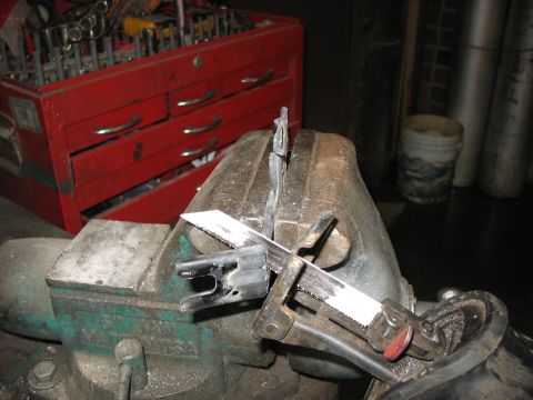 1995 Ford C-350 (Centurion Conversions) - Cutting a metal bracket with a reciprocating saw in a workshop setting.