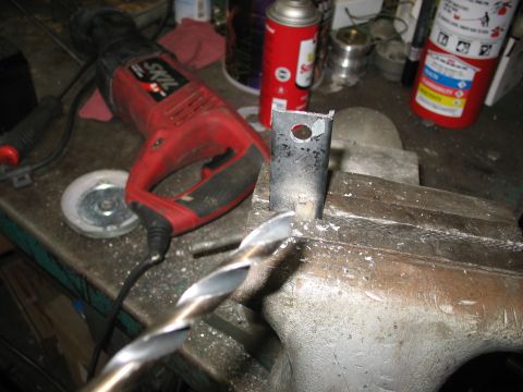 1995 Ford C-350 (Centurion Conversions) - A metal bracket is secured in a vise and being drilled, with a reciprocating saw and drill bit visible on the workbench.