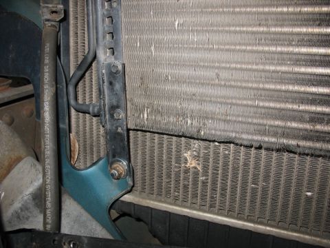 1995 Ford C-350 (Centurion Conversions) - Close-up view of the radiator and intercooler assembly, showing damage and wear. A fuel line with printed specifications is visible.