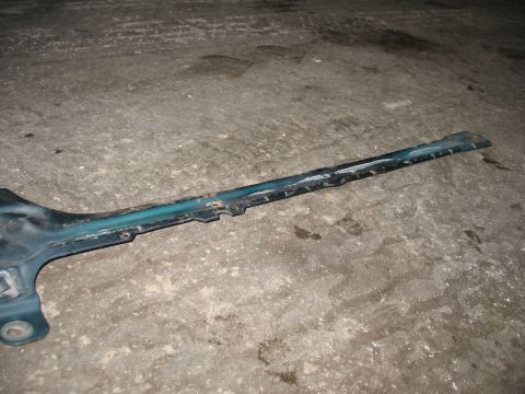 1995 Ford C-350 (Centurion Conversions) - A weathered metal part, possibly from a vehicle's frame, rests on a textured concrete floor.