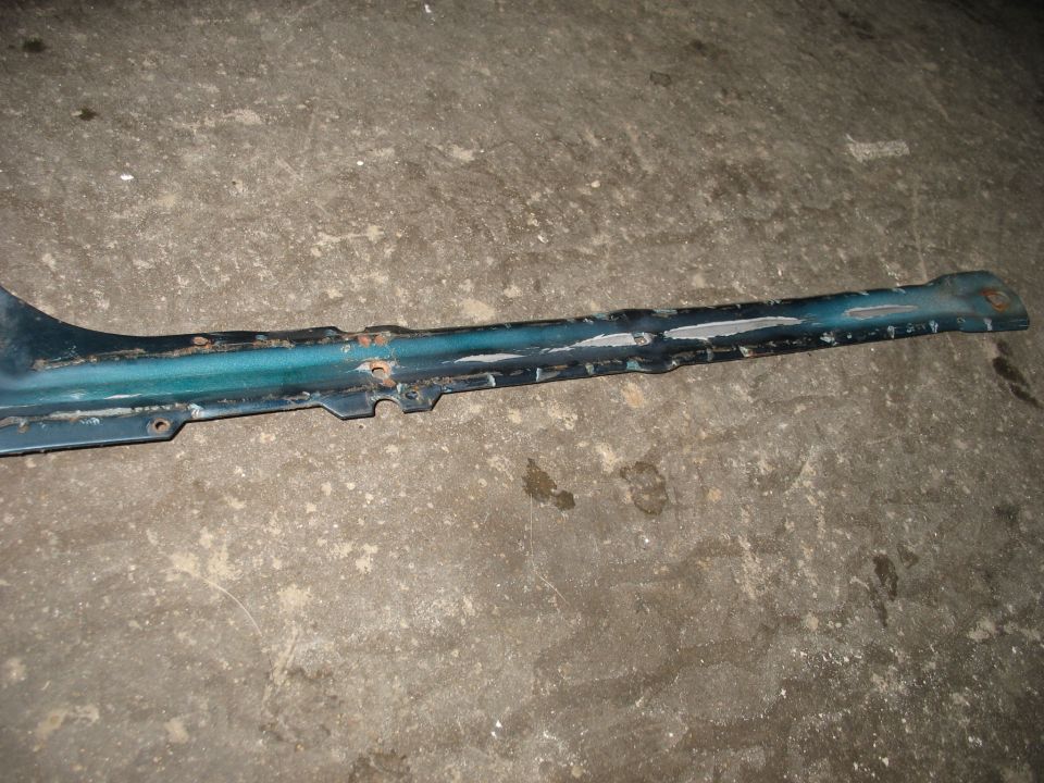 Long teal stamped steel support brace with chipped paint on concrete floor