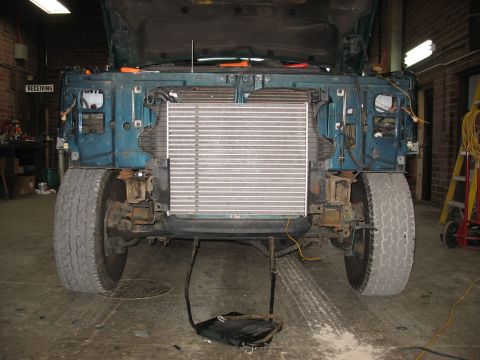 1995 Ford C-350 (Centurion Conversions) - The front of a vehicle is disassembled, with the radiator removed and parts laid out on the floor.