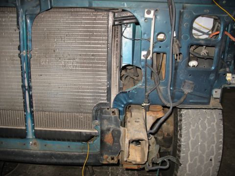 1995 Ford C-350 (Centurion Conversions) - Close-up view of a vehicle's front end, focusing on the radiator and surrounding engine bay components, with a tire visible on the right.
