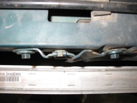 1995 Ford C-350 (Centurion Conversions) - Undercarriage view of a vehicle's mounting bracket, showing fasteners and a clip mechanism.