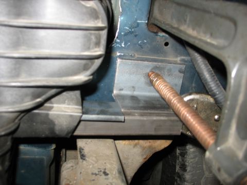 1995 Ford C-350 (Centurion Conversions) - Close-up view of a copper pipe being installed into a metal bracket in the engine bay.