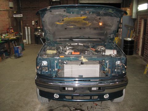 1995 Ford C-350 (Centurion Conversions) - Front view of a truck with its hood up, revealing the engine and a newly installed intercooler in a workshop setting.
