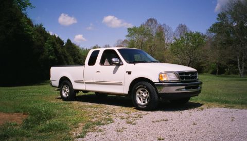 2007 Ford Mustang - This white 1998 Ford F-150 Supercab pickup truck is seen from a three-quarter front view, parked outdoors on a sunny day.