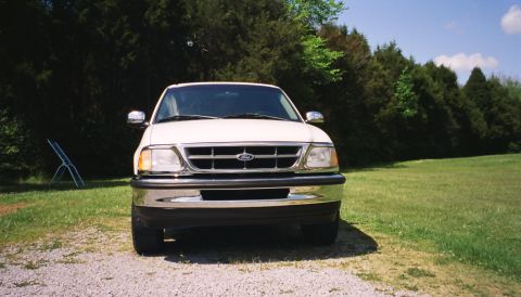 2007 Ford Mustang - This Ford F-150 pickup truck is shown from the front, parked on a gravel surface with a grassy area and trees behind it.