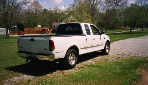 2007 Ford Mustang - This white 2007 Ford F-150 SuperCab pickup truck is seen from the rear 3/4 angle parked on a gravel driveway.