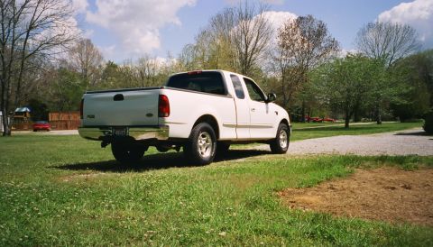2007 Ford Mustang - White Ford F-150 SuperCrew pickup truck parked on grass with trees and a cloudy sky in the background.