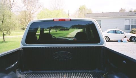 2007 Ford Mustang - View from inside a pickup truck bed shows the Ford logo on the tailgate and a white sedan being washed.