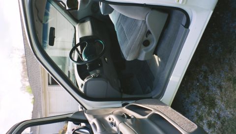 2007 Ford Mustang - The interior of a white pickup truck is visible through the open driver's side door, revealing the seats and steering wheel.