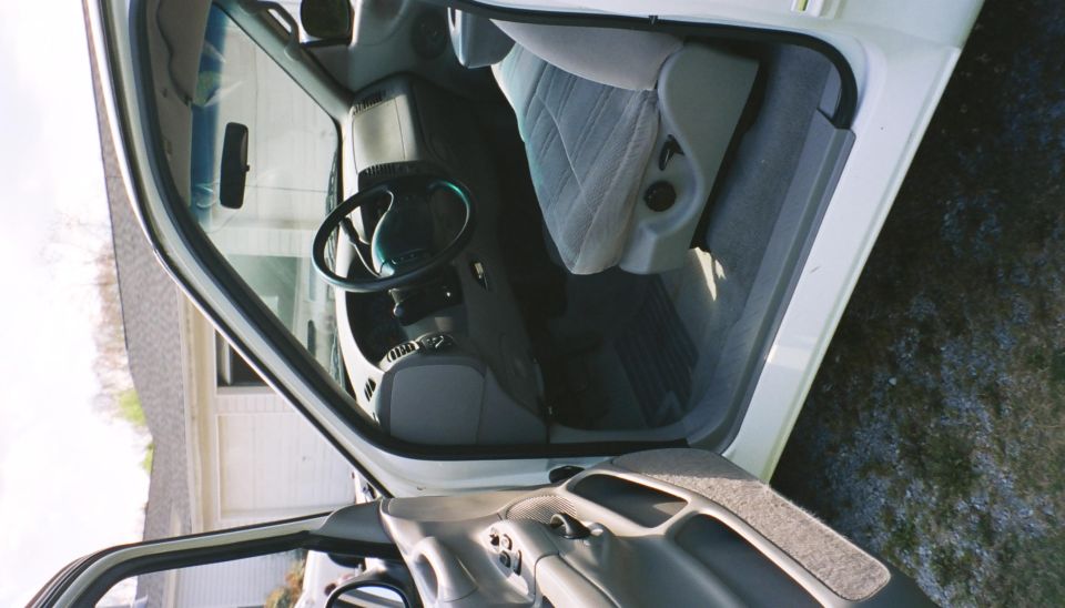 Interior of a white pickup truck, showing the driver's seat and dashboard