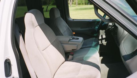 2007 Ford Mustang - The interior of a truck shows fabric seats and a center console with a cup holder.