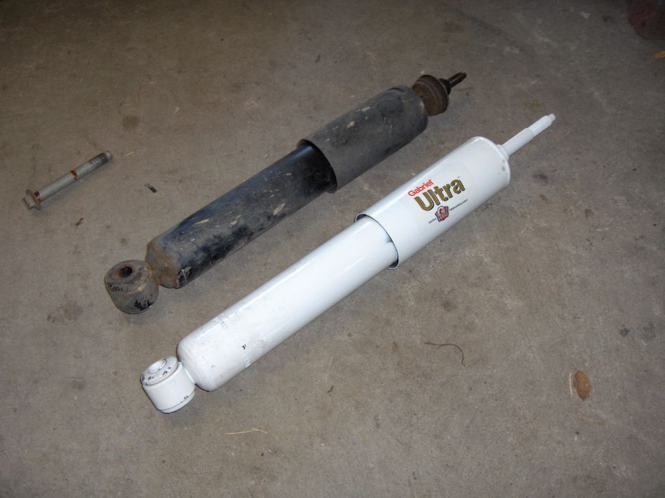 New white Gabriel Ultra shock absorber next to an old black shock absorber on a concrete floor