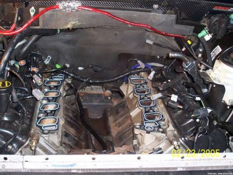2007 Ford Mustang - The engine bay is shown with the intake manifold removed, revealing the complex wiring and engine components.