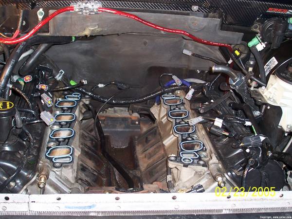 Engine bay with intake manifold removed, showing wiring and engine block