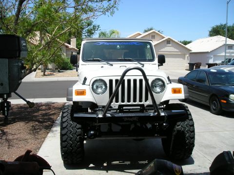 1986 Toyota Hilux - A white Jeep Wrangler is parked in front of a suburban house, with a black sedan visible to its right.