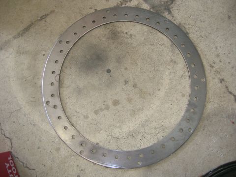 1996 Ford Bronco - A circular metal part with numerous small holes is shown lying on a concrete floor.