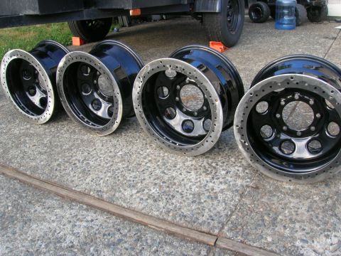 1996 Ford Bronco - A set of four black off-road wheels with polished lips are displayed on a concrete surface.