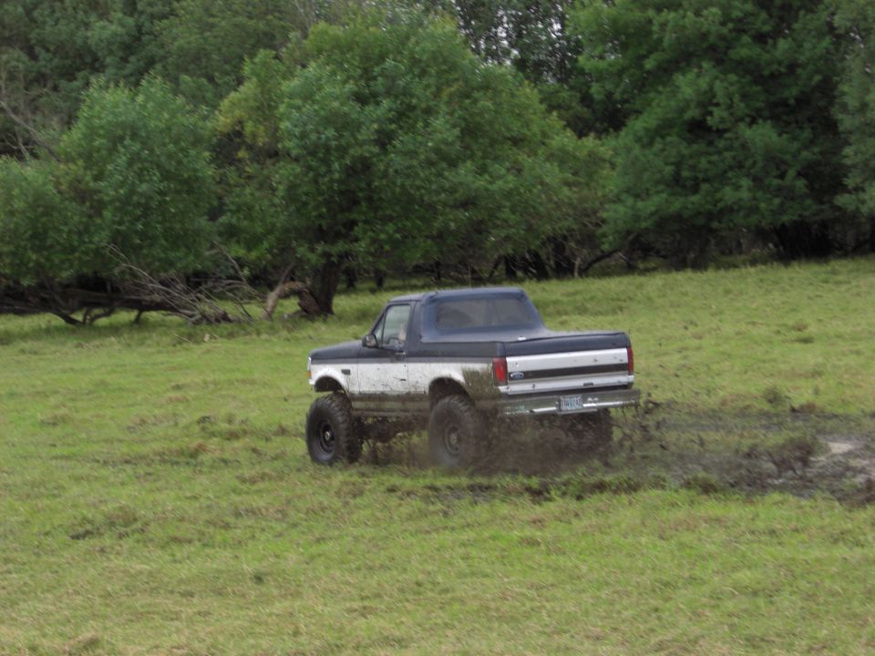 1993 Ford Bronco kicking up mud while driving off-road