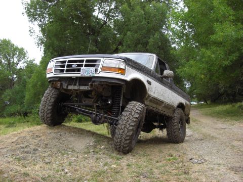 1993 Ford Bronco - Modified 1993 Ford Bronco tackling an off-road trail with its suspension articulated.