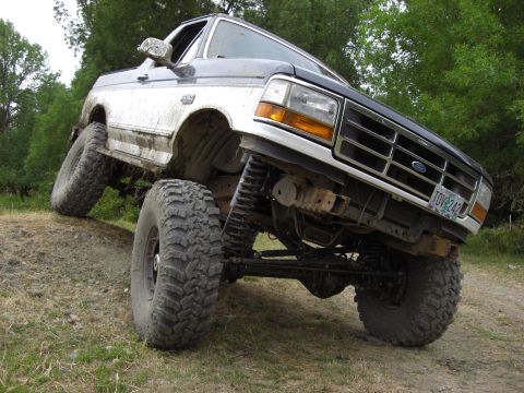 1993 Ford Bronco - This lifted Ford Bronco is shown navigating an off-road trail with one wheel significantly elevated.