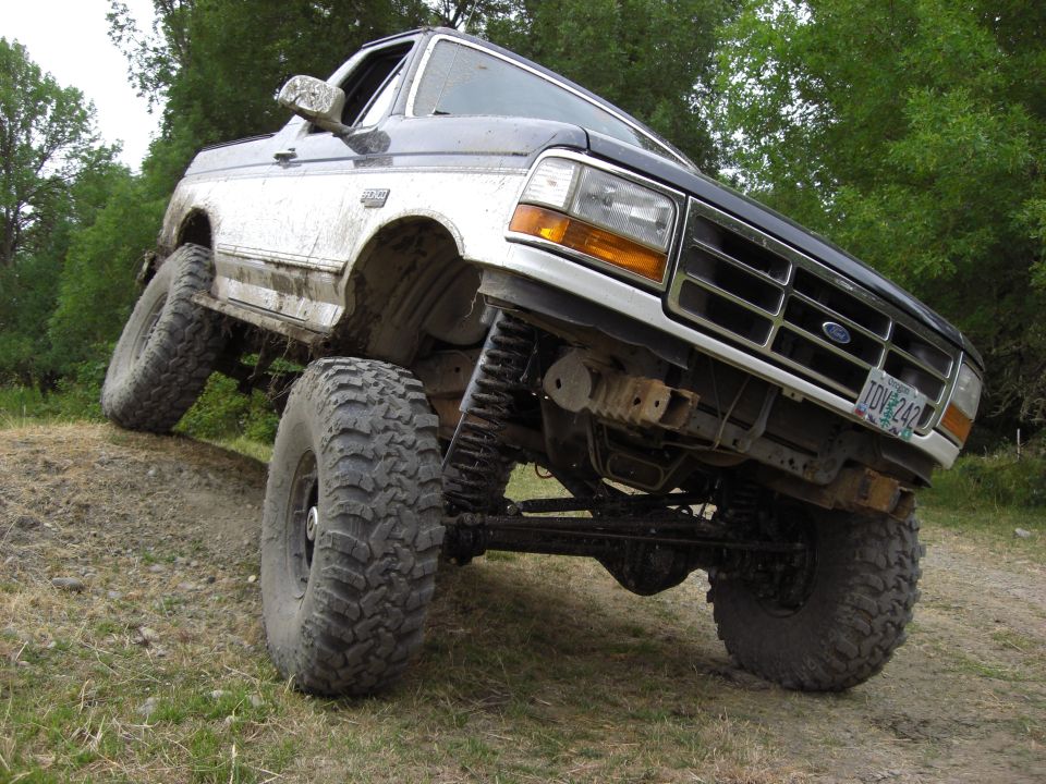 1993 Ford Bronco climbing dirt hill, front right tire high off ground