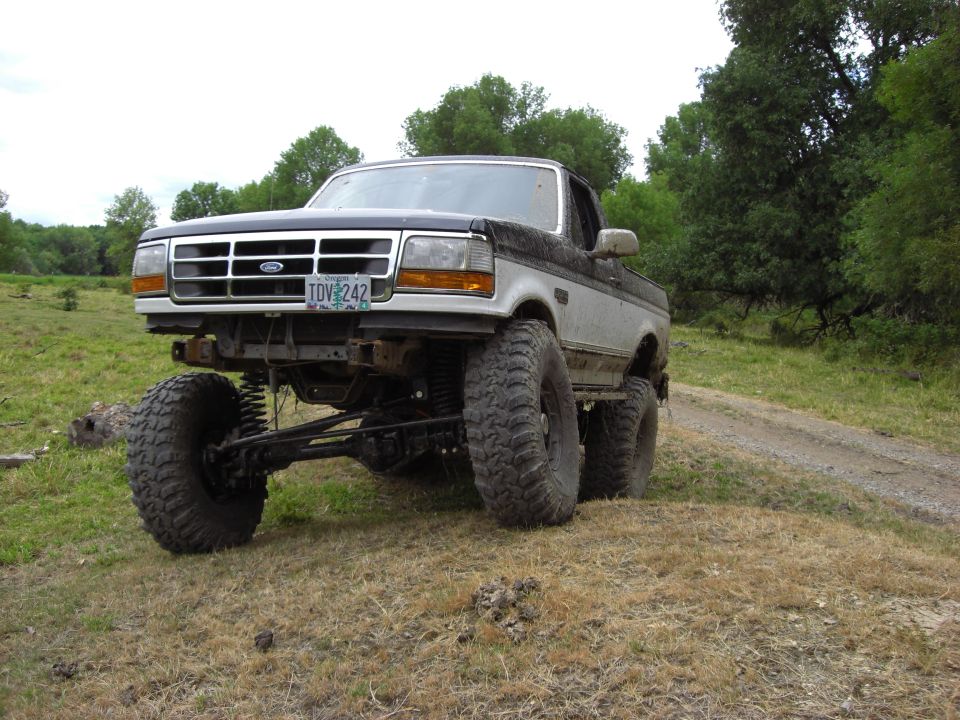 Modified Ford F-Series pickup truck with large tires and suspension lift, front view. License plate reads TDV 242